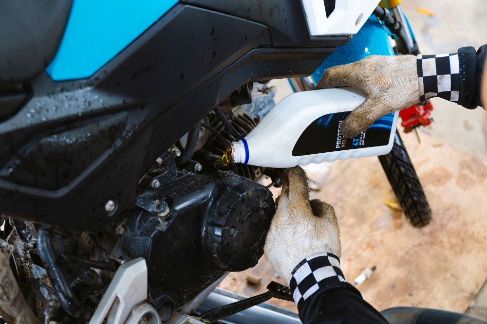 Motork&aacute;ř dol&eacute;v&aacute; olej u sv&eacute; motorky v gar&aacute;ži