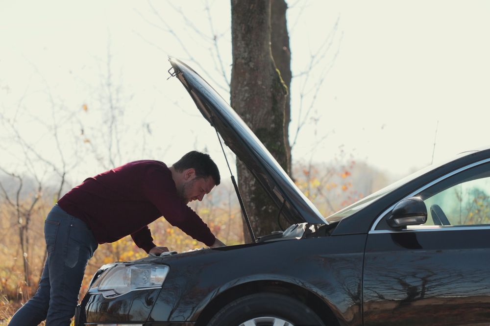 Muž u otevřené kapoty řeší poruchu motoru