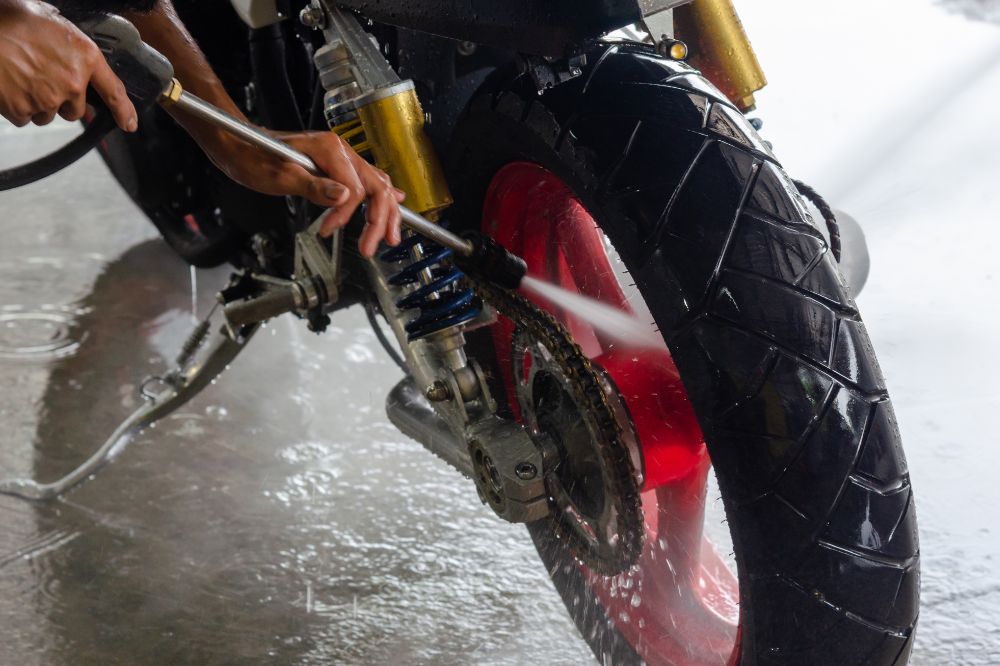 Muž v myčce umývá motorku vysokotlakým čističem