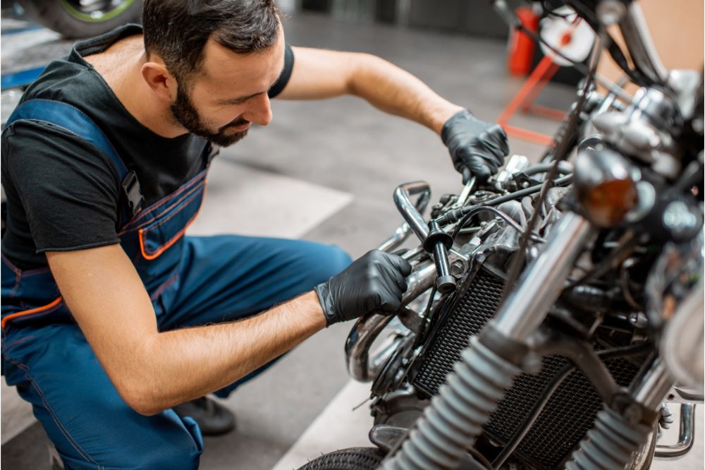 Mechanik v servisu opravuje motor motocyklu