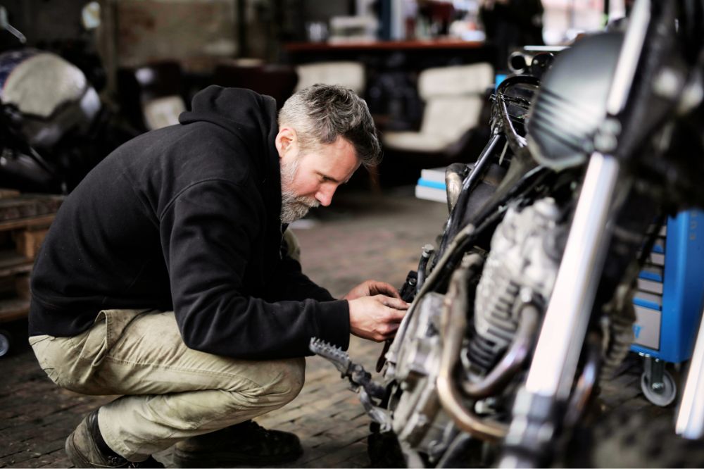 Muž v gar&aacute;ži kontroluje důležit&eacute; souč&aacute;sti motorky