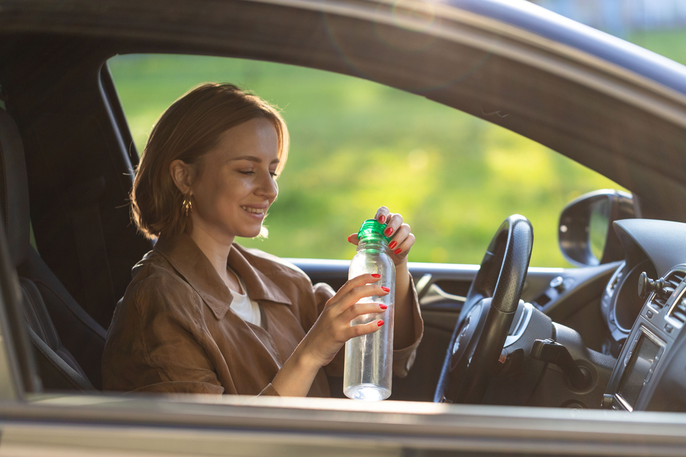 Řidička drží láhev vody