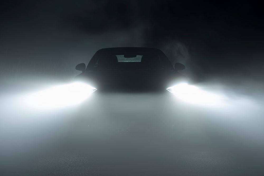 Auto v mlze sv&iacute;t&iacute; na cestu předn&iacute;mi mlhov&yacute;mi světly