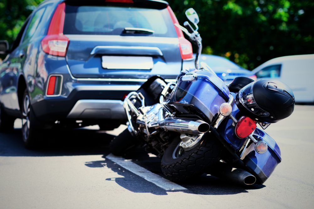 Motorka lež&iacute; na vozovce za automobilem po men&scaron;&iacute; dopravn&iacute; nehodě