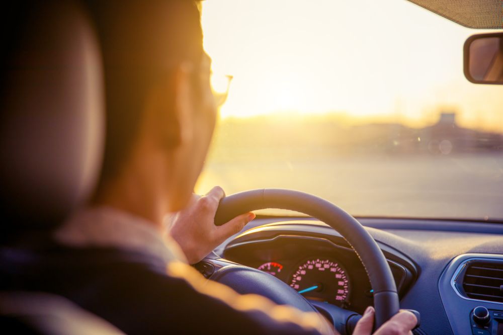 Muž řídí auto proti západu slunce