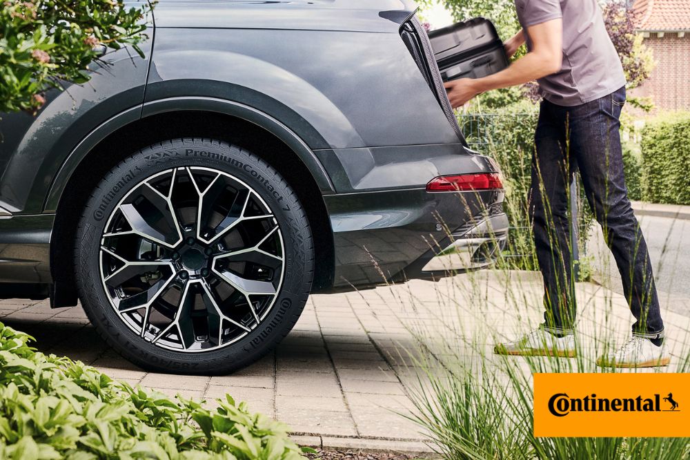 Muž nakládá zavazadlo do kufru auta, které má obuté pneumatiky Continental