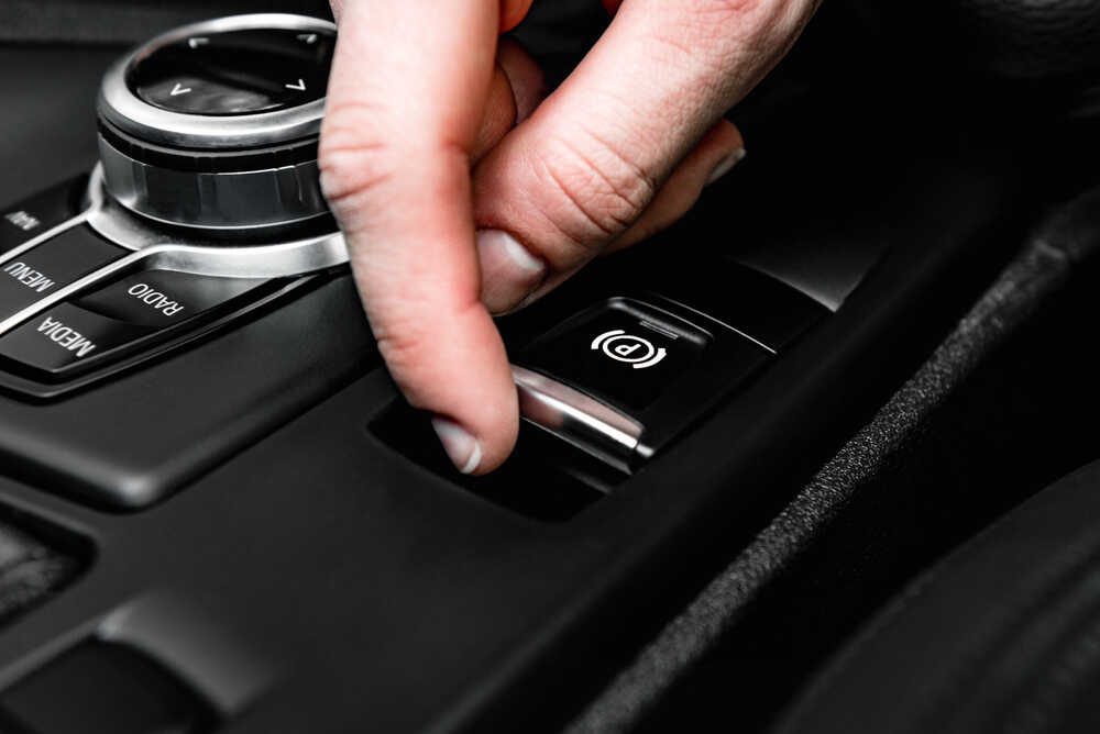 Řidička aktivuje automatickou ruční brzdu stisknutím tlačítka