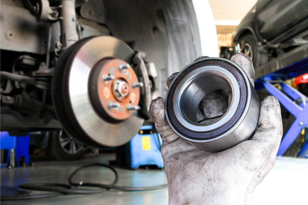 Mechanik v autoservisu drž&iacute; v ruce nov&eacute; ložisko